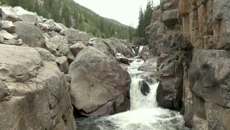 Aerial-rising-out-of-canyon-with-waterfall-and-river-in-Colorado