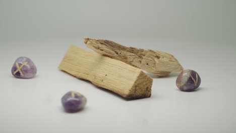 Two-cuts-of-Palo-Santo-wood-and-four-purple-white-colored-stone-displayed-on-a-turntable---medium-shot