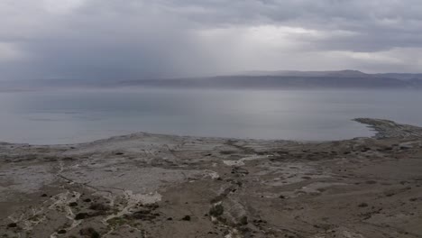 dead-sea-shore-fly-down-and-focus-on-flood-water,-cloudy-day,-Israel