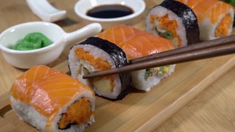 Recogiendo-Sushi-De-Una-Tabla-De-Servir-De-Bambú-Con-Palillos