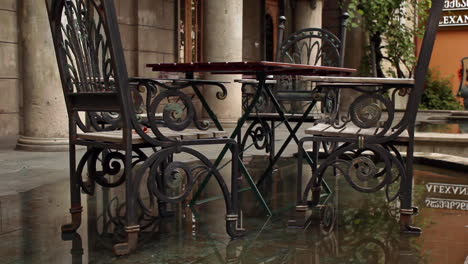 Street-cafe-with-metal-tables-and-chairs-on-wet-ground-in-Batumi,-Georgia