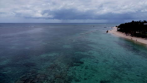 Aerial-backwards-shot-of-paradise-island-with-stormy-rain-in-background