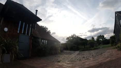 Time-lapse-from-a-Kentish-barn-conversion-from-day-to-night,-with-dogs-playing-outside