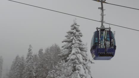 Gondola-lift-moving-upwards-during-heavy-snowfall-with-skis-und-skiers-inside,-close-up-shot