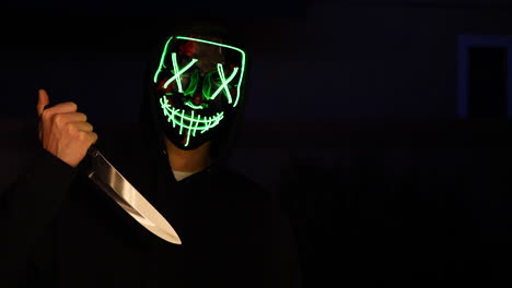 Ein-Gruseliger-Slasher-Killer-In-Einer-Generischen-Anonymen-Halloween-Horrormaske,-Der-Ein-Messer-Auf-Sein-Mordopfer-Zieht
