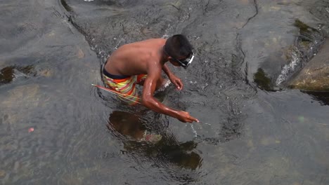 A-Close-up-shot-of-a-Thai-boy-spear-fishing-wearing-a-diving-mask-in-a-river-slow-motion-close-up-shot