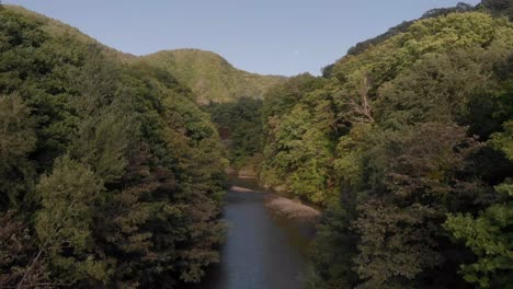 Luftaufnahme,-Die-Sich-Langsam-über-Dichtem-Grünen-Wald-Und-Fluss-In-Der-Berühmten-Onsen-stadt-Jozankei-Mit-Heißen-Quellen-In-Hokkaido,-Japan,-Erhebt