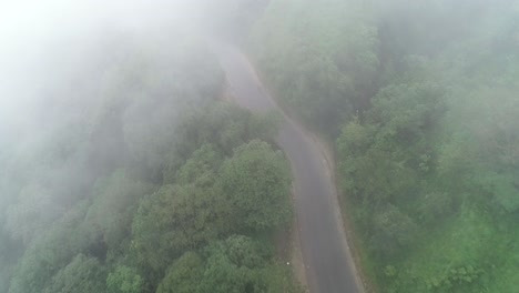 Aerial-shot-over-countryside-curvy-road-on-a-foggy-day