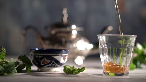 Cinemagraph-Des-Tees,-Der-Mit-Marokkanischem-Teeset-Und-Minze-In-Ein-Glas-Gegossen-Wird