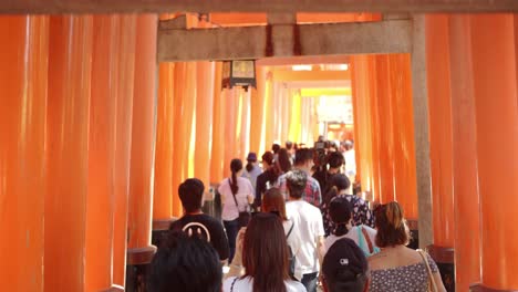 Crowd-of-people-walking-through-a-tunnel-of-Japanese-Tori's-in-Kyoto,-Japan-soft-lighting-slow-motion-4K