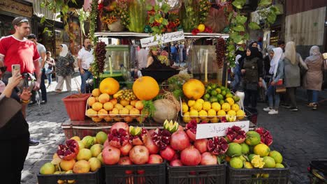 Man-in-red-t-shirt-looking-at-the-fruit-juice-stall-along-the-street-in-Syria-Damascus,-steady-shot