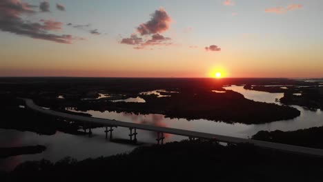 Aerial-view-falling-back-from-a-bridge,-showing-a-beautiful-sunset-over-the-beautiful-Manatee-River-in-Bradenton,-Florida