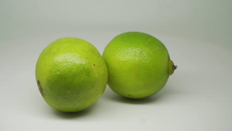 Zwei-Grüne-Saure-Zitronen,-Die-Sich-In-Kreisbewegung-Bewegen---Nahaufnahme