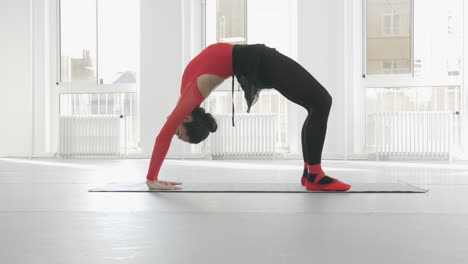 Ballerina-does-the-bridge-exercise-in-a-white-dance-studio