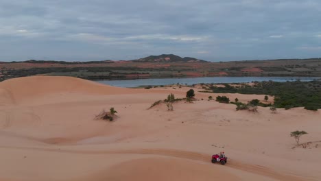 Cinematic-aerial-drone-shot-following-ATV-quad-riding-through-the-sand-dunes-of-vietnam-during-golden-sun-rise