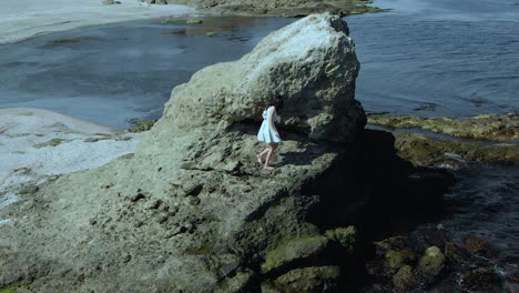 Pretty-girl-in-white-dress-climb-big-cliff-on-seashore---59
