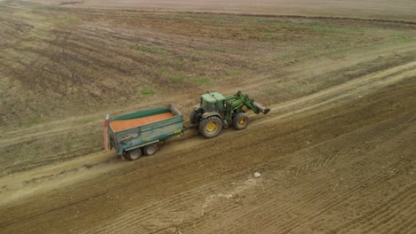 Tractor-with-trailer-transport-seed-in-field---aerial-tracking-shot-1