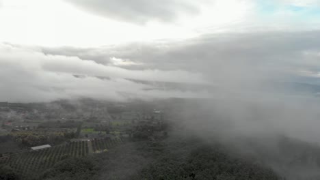 Filmische-Luftdrohne,-Die-An-Einem-Kalten-Morgen-In-Thailand-Durch-Neblige-Wolken-Fliegt,-Um-Ein-Abgelegenes-Dorf-Im-Tal-An-Berghängen-Zu-Enthüllen