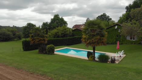 Cinematic-aerial-revolve-around-private-pool-in-french-villa-in-the-quiet-countryside-of-france-on-overcast-afternoon