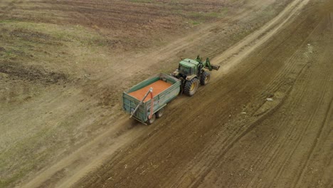 Traktor-Mit-Anhänger-Transportiert-Saatgut-Im-Feld---Kamerafahrt-Aus-Der-Luft
