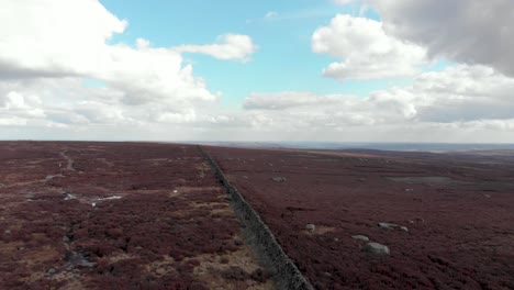 Aerial-rising-drone-view-of-English-countryside-moorland-on-windy-clear-blue-day