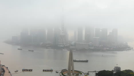 Descending-drone-revealing-the-Monument-to-the-People's-Heroes-and-the-busy-Waibaidu-Bridge-on-a-dense-foggy-day