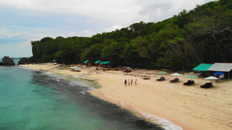 Drohnenvideo-Von-Vier-Menschen,-Die-An-Einem-Wunderschönen-Weißen-Sandstrand-Spazieren-Gehen,-Aufgenommen-In-Bali,-Indonesien