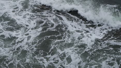 Big-splash-of-waves-on-foamy-sea-waters,-wide-shot-in-slow-motion