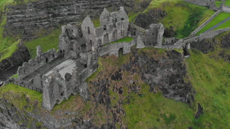 Tilted-top-down-drone-view-flying-over-medieval-castle-ruins-on-the-edge-of-a-basalt-outcropping-near-the-Atlantic-Ocean