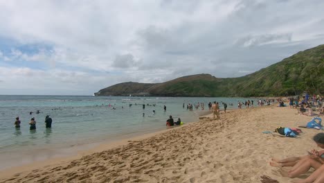 Tourist-enjoying-paradise-by-sunbathing-and-playing-in-the-water-at-Hanauma-Bay-State-Park-and-Nature-Preserve-on-Oahu-Island-in-Hawaii-on-a-cloudy-day