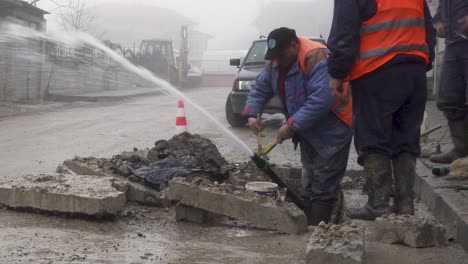 Stadtarbeiter-Reparieren-Eine-Kaputte-Wasserleitung-Mit-Wasser,-Das-Auf-Der-Ganzen-Straße-In-Bulgarien-Spritzt