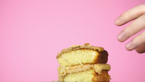 Slow-motion-of-a-hand-moving-in-to-take-a-slice-of-cake-against-a-pink-background