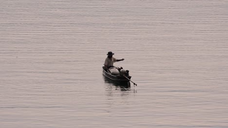 Fisherman-silhouetting-as-he-is-casting-and-drawing-his-net-in-the-River-before-dark,-in-slow-motion