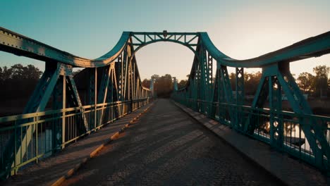 Caminando-Sobre-Un-Puente-Verde-De-Metal-Al-Amanecer-En-Polonia