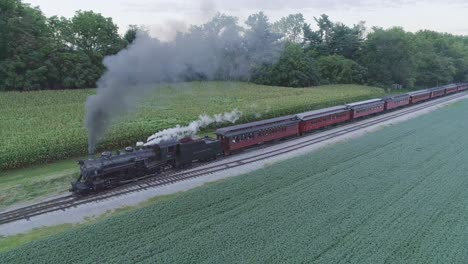 Aerial-View-on-a-Steam-Passenger-Train-Leaving-a-Train-Station-in-the-Amish-Countryside-on-a-Summer-Day