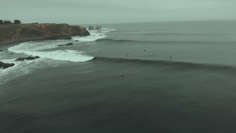 Aerial-Drone-Shot-following-wave-flying-backwards-on-a-cold,-dark-day-in-Pichilemu,-Chile-4K