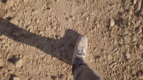 Feet-walking,-hiking-on-desert-ground-of-rocks-and-sand