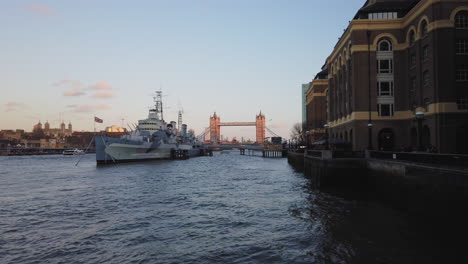 Calm-panning-view-of-HMS-Belfast-ship,-tower-and-bridge-of-London-over-Thames-river