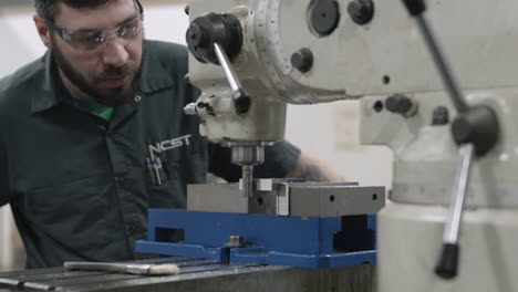 Trade-school-machining-student-carefully-grinding-a-precision-part-on-an-industrial-milling-machine