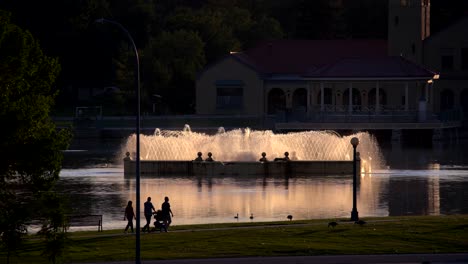 People-walking-in-the-City-Park-of-Denver,-Colorado-against-a-background-of-lake-and-water-fountain