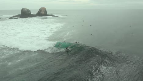 Aerial-Shot-of-Pro-Surfer-riding-wave-and-doing-tricks-on-a-cloudy-day-in-Pichilemu,-Chile-4K