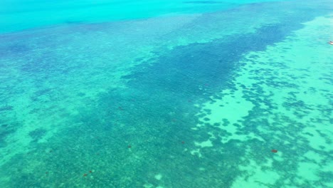 Sea-texture,-blue-turquoise-water-with-coral-reef-and-white-sand-on-the-seafloor