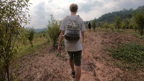 Mehrere-Junge-Männer,-Die-Während-Der-Gibbon-Erfahrung-In-Den-Feldern-Von-Laos-Wandern-Und-Obstbüsche-Zeigen