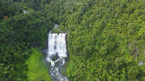 Aerial-shot-of-white-and-blue-waterfall-in-dense-green-forest