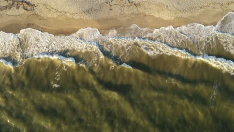 Vertical-shot-of-the-ocean-waves-crashing-on-the-shoreline
