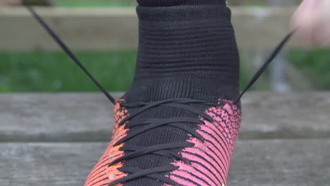 Man-tying-soccer-shoe-in-slow-motion,-close-up