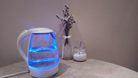 Water-boiling-with-bubbles-in-neon-transparent-electric-kettle,-nice-kitchen-background,-hot-water-for-making-tea