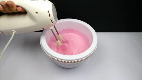 A-woman-is-making-a-strawberry-ice-cream-with-its-pink-color-into-the-pan-with-mixer