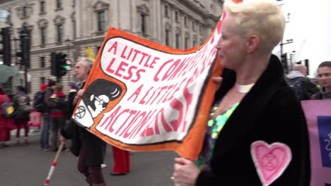 Extinction-Rebellion-climate-change-protestors-march-with-a-large-banner-saying-“A-little-less-conversation-a-little-more-action-please”