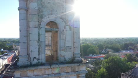 Extreme-Nahaufnahme-Aus-Der-Luft-Des-Hintergrundbeleuchteten-Glockenturms-Mit-Sonne,-Die-Am-Rand-Glänzt,-Während-Sich-Die-Kamera-Langsam-über-Die-Catedral-De-San-Gervasio-In-Valladolid,-Yucatan,-Mexiko-Erhebt